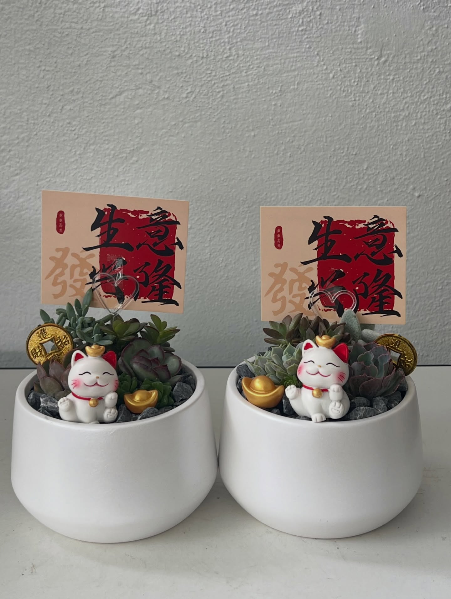 A pair of fortune cat succulent pots with gold ingots and a prosperity card